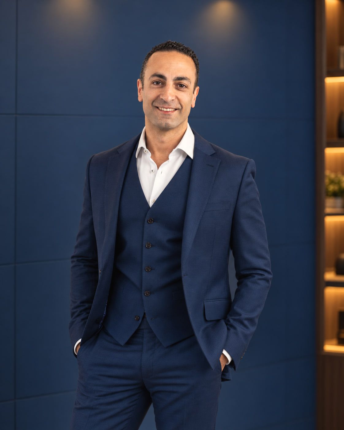 Mr Haider Jan in a navy three-piece suit and tie, standing with one hand in his pocket.